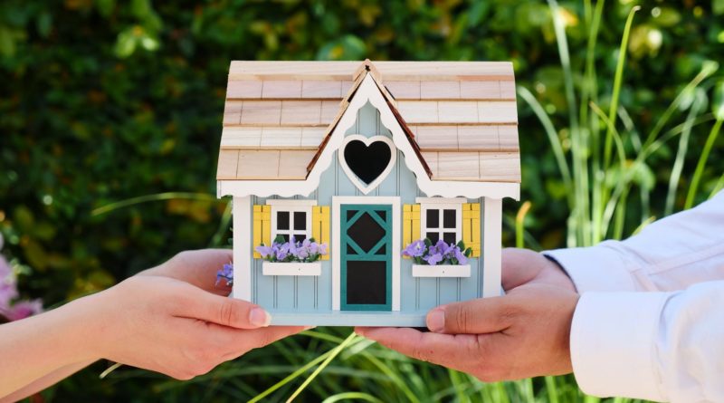 people holding miniature wooden house