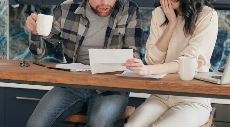 a couple sitting near the wooden table while looking at the document in shocked emotion